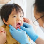 乳歯が虫歯になり歯医者に口の中を見せる男の子
