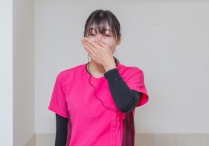口に手を当てた女性スタッフ
